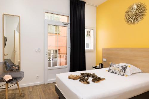 a bedroom with a bed and a yellow wall at Hôtel Byakko Nice in Nice