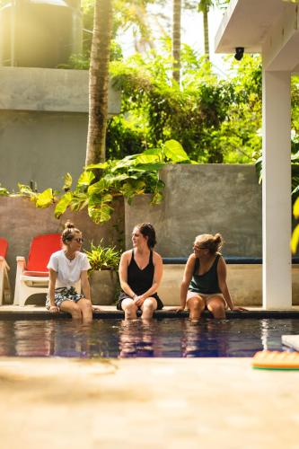 three women sitting on the ground by a pool at Salt House in Hiriketiya