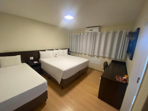 a hotel room with two beds and a window at HD Plaza Hotel in Assis