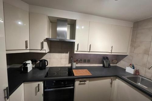 a kitchen with white cabinets and a stove and a sink at Vibrant & Homely 2BD Flat - Angel in London