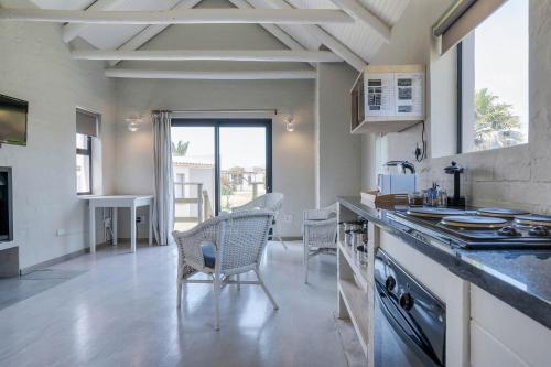 a kitchen with a counter and chairs in a room at Blue Bay Lodge in Saldanha