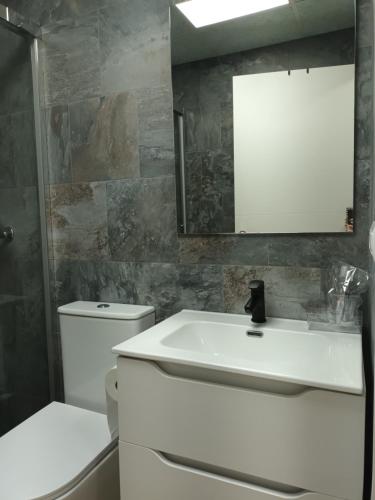 La salle de bains est pourvue d'un lavabo blanc et d'un miroir. dans l'établissement Hostal Cerro del Castillo jumilla, à Jumilla