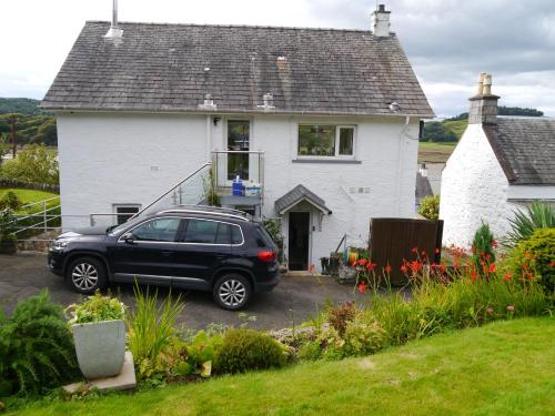 a black car parked in front of a white house at Phoenix Cottage in Kippford