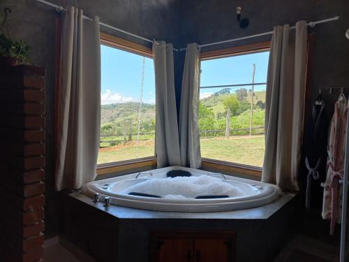 a bath tub in a room with two windows at Chalé Araucária- Vale das Pedras MG in Sapucaí-Mirim