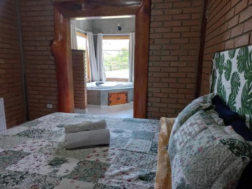 a bedroom with a large bed with a brick wall at Chalé Araucária- Vale das Pedras MG in Sapucaí-Mirim