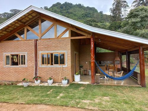 a house with a hammock in front of it at Chalé Araucária- Vale das Pedras MG in Sapucaí-Mirim