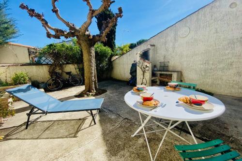 een tafel en stoelen op een patio met een boom bij La Maison des Sauges - Village house with garden 500m from the beach in Le Grau-du-Roi