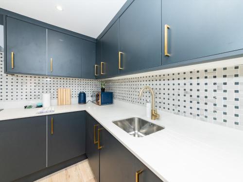 a kitchen with blue cabinets and a sink at Pass the Keys Brand New Stylish 2BR Flat in Reading Centre in Reading
