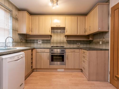 a kitchen with wooden cabinets and a stove top oven at Pass the Keys - Cosy Maisonette with Garden in Central East London in London