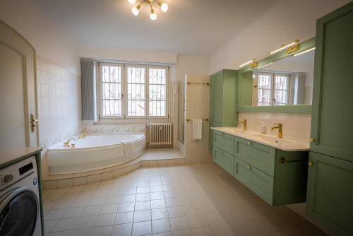 bagno con vasca, lavandino e lavatrice di Gîte de la mairie a Kaysersberg