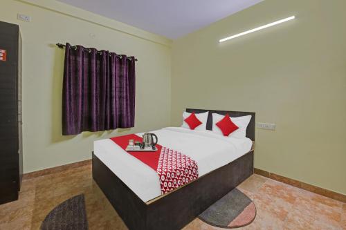 a bedroom with a bed with red pillows at Flagship Honnagiri Residency in Bangalore