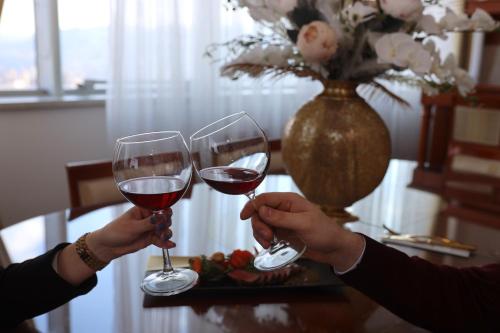 two people holding glasses of red wine on a table at Apart-hotel Integra in Banja Luka