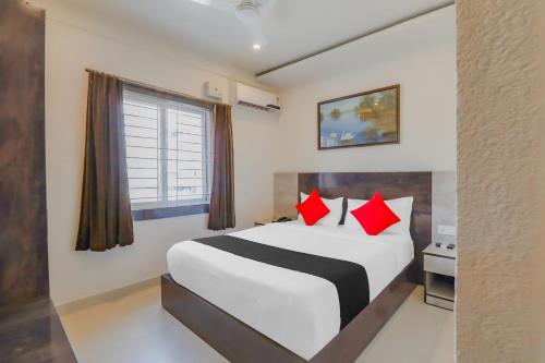 a bedroom with a large bed with red pillows at Capital O Royal Galaxy Finesse Near Phoenix Marketcity in Bengaluru