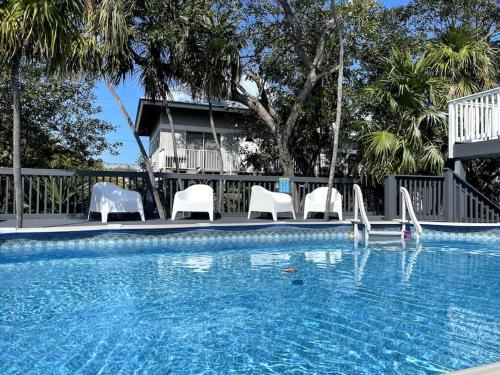 a swimming pool with white chairs and a swimming pool at PARADISE AT SUNSET in Marathon