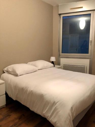 1 dormitorio con cama blanca y ventana en Appartement de 110m2 au centre de Cusset en Cusset