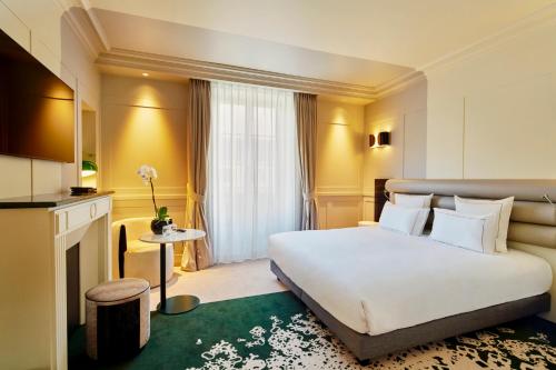 a hotel room with a large white bed and a fireplace at La Licorne Hotel & Spa Troyes - MGallery Collection in Troyes