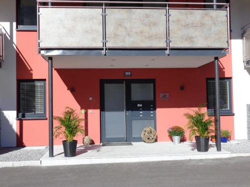 a red building with a door and two potted plants at K3 - Appartements in Strobl