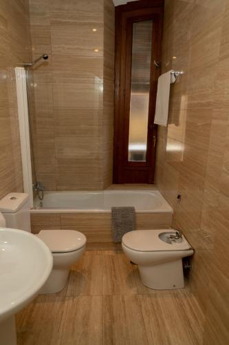 a bathroom with two toilets and a sink and a tub at Suite Alhambra Puerta Bib-Rambla in Granada
