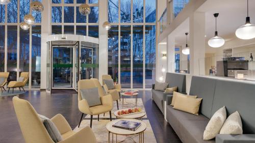 a lobby with a couch and chairs and windows at Hotel the YARD Bad Honnef in Bad Honnef am Rhein