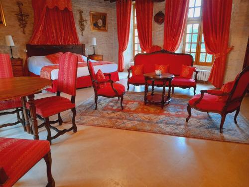 a bedroom with red furniture and a bed and a table and chairs at Hôtel Le Manoir De Mathan Crépon à la campagne 5 mn d'Arromanches et 10 mn de Bayeux in Crépon