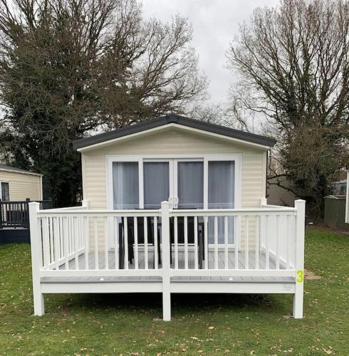 uma pequena casa branca com um corrimão branco em Kellysholidayhomes NEW Malton 3 bedroom Caravan em Weeley