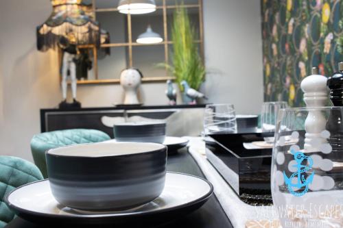 una mesa con un tazón blanco y negro en un plato en La Petite Maison Apartments en Brixham