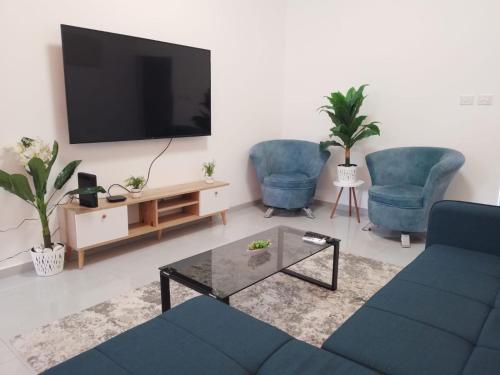 ein Wohnzimmer mit 2 blauen Stühlen und einem Flachbild-TV in der Unterkunft Puy Rambam's apartment Tiberias in Tiberias