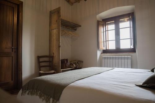 a bedroom with a bed and a window and a chair at La Casa Di Campagna in Magione