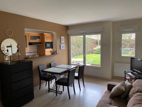 een woonkamer met een tafel en stoelen en een bank bij Appartement Cosy, tout confort, à deux pas de la mer in Deauville