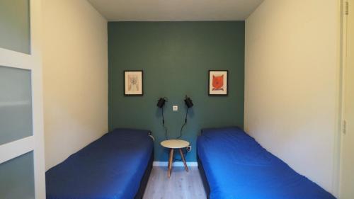 een kamer met twee blauwe bedden en een tafel bij Veluwe Nature Home - 2-4 persons in Otterlo