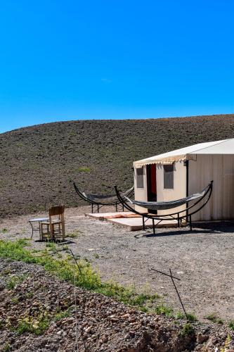 a building with two benches and a hammock next to it at Camp Cameleon in Marrakech
