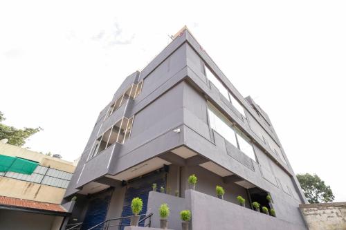 OYO Flagship NEW TOWNHOUSE في بانغالور: مبنى رمادي أمامه نباتات خزف