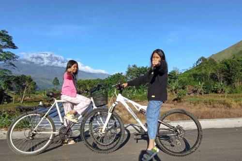 Deux filles font leur vélo sur la route dans l'établissement Sada 360 homestay, à Sembalun Lawang