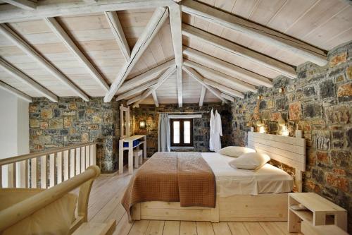 - une chambre avec un lit et un mur en pierre dans l'établissement Villas Palazzo Greco, Agia Galini, à Agia Galini