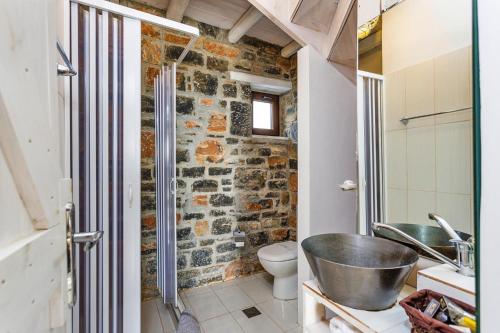 La salle de bains est pourvue d'un mur en pierre, d'un lavabo et de toilettes. dans l'établissement Villas Palazzo Greco, Agia Galini, à Agia Galini