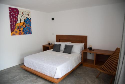 een slaapkamer met een bed, een bureau en een schilderij bij Casa Naâmja in Tepoztlán