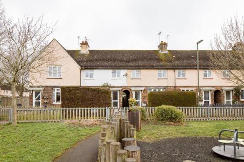 a house with a wooden fence and a playground at Littlehaven in Roffey