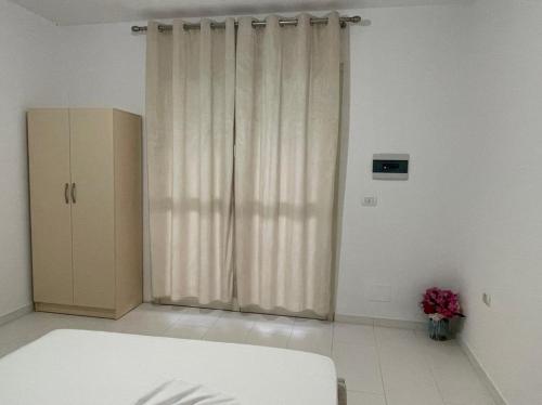 a room with a curtain and a cabinet and flowers at Marios Rooms in Vlorë