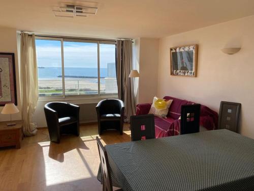 a living room with a couch and chairs and a large window at Appartement face à la mer in Cap d'Agde