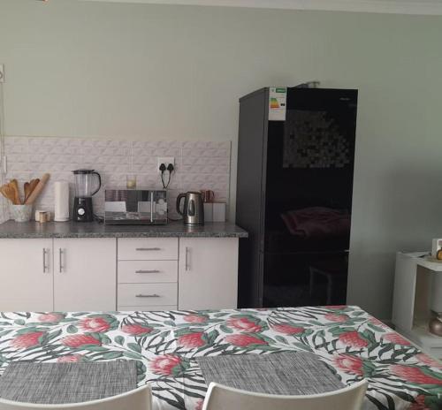 a kitchen with a bed with a flower pattern on it at Inkazimulo Airbnb in Estcourt