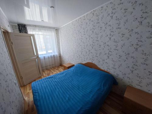 Un dormitorio con una cama azul y una ventana en Квартира посуточно, en Shchūchīnsk
