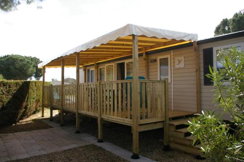 een houten hut met een tent op een terras bij Mobile Home OuiReves 344 facing the Mediterranean in Lattes