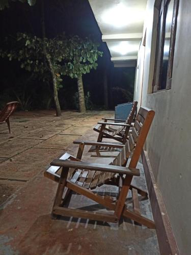 three wooden chairs sitting on a porch at night at Seaface Rest Homestay in Hambantota