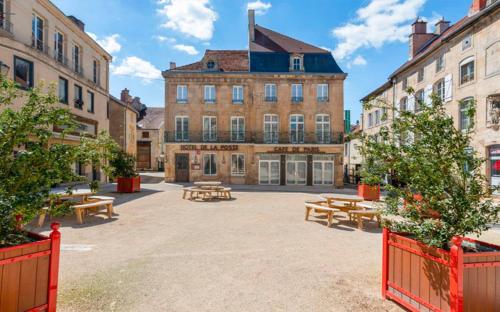 un patio con mesas de picnic frente a un edificio en Hotel De La Poste en Langres