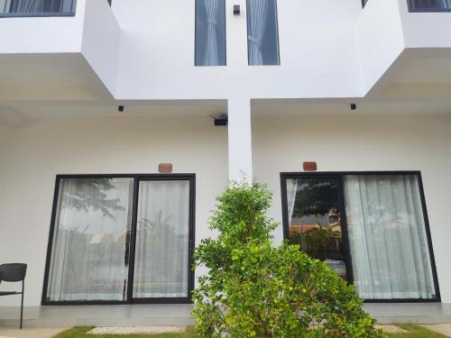 a white building with glass doors and a plant at H&M Boutique in Kampot