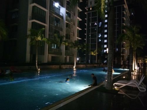 two people in a swimming pool at night at Damai Homestay Almyra in Kajang