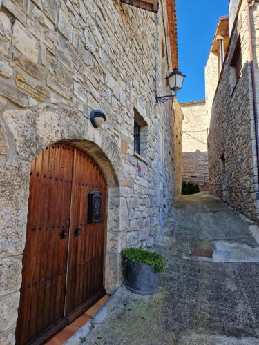 a stone building with a wooden door in a alley at Cal Bisbe in Segura
