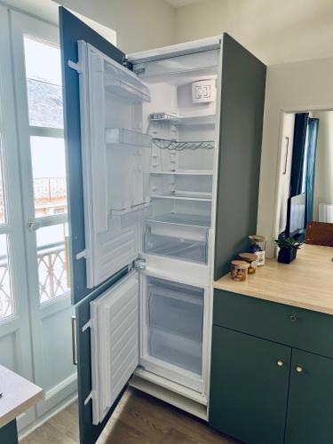 an empty refrigerator with its door open in a kitchen at Studio Remigny, hyper centre ville de Nevers, style "Appart-hôtel" by PRIMO C0NCIERGERIE in Nevers