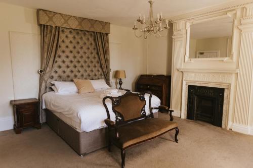 a bedroom with a bed and a chair and a fireplace at Healing Manor Hotel in Grimsby