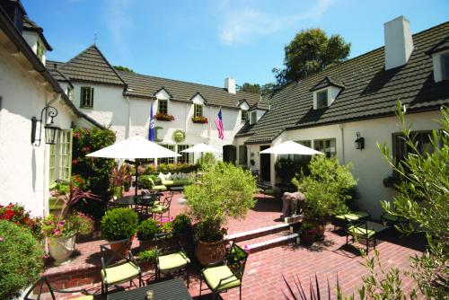 an outdoor patio with tables and chairs and umbrellas at L'Auberge Carmel, Relais & Chateaux in Carmel